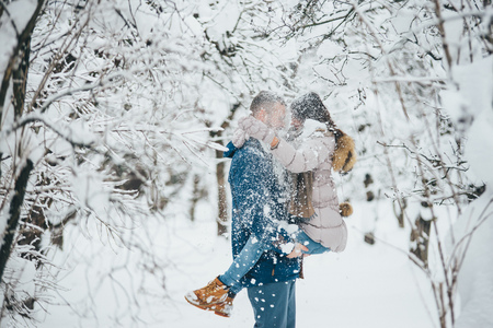 Lovely couple hugging and playing in snowfall, embracing their love and happinessの写真素材
