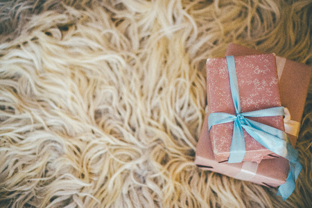 Pair of Christmas gifts wrapped in pink and blue ribbons laying on the fluffy rugの写真素材