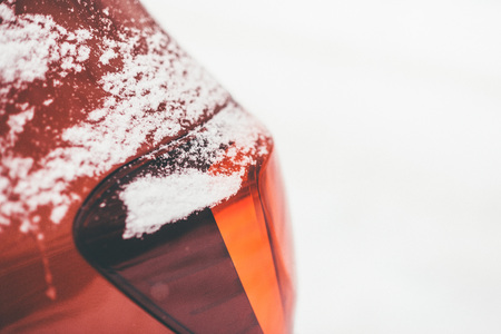 Closeup shot of red cars rear headlight covered with flaky snow on the snow white backgroundの写真素材