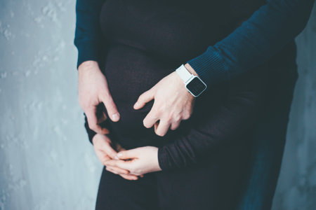 man and woman hugging pregnant belly in black