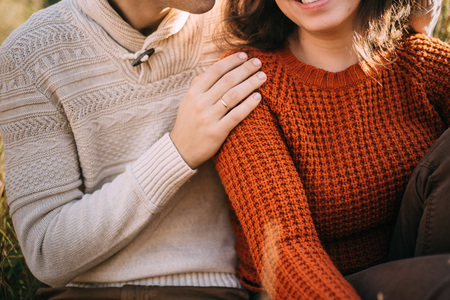loving couple is hugging sitting in the grass sunshine autumn hands close upの写真素材