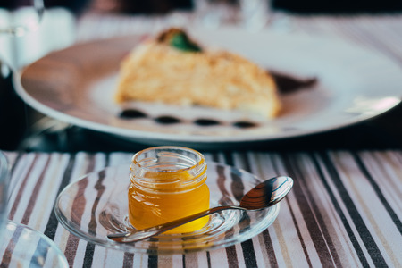 jar of honey on the plate with tasty Napoleon cake on the background on the plateの写真素材