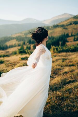 woman in wedding dress is staying in the mountains strong wind autumnの写真素材
