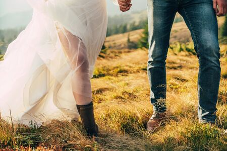 woman in wedding dress with warm shoes boots walking in the mountains autumn, jeansの写真素材