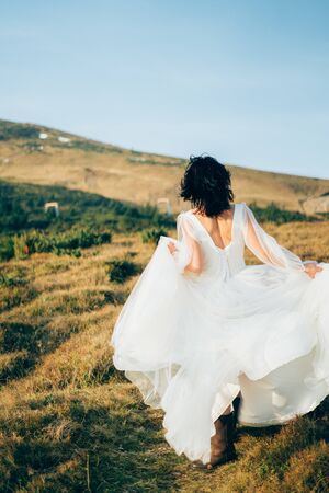 woman in wedding dress is staying in the mountains strong wind autumnの写真素材