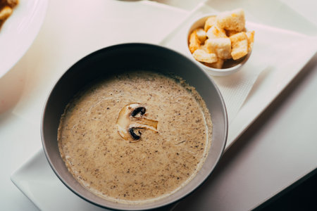 Mushroom cream soup with crackers close up on the white table in the restaurant