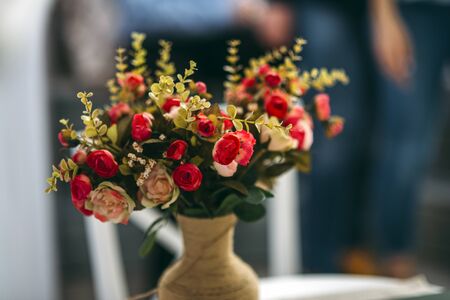 beautiful red rose flowers in the brown vase dark background green leaves presentの写真素材