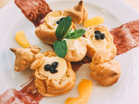 profiteroles with cream and orange cream and mint leaves on the plate