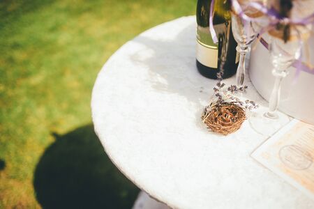Wedding rings in a little decorative nest with a sprig of lavander on the white, round table. Close up, outoor wedding conception.の写真素材