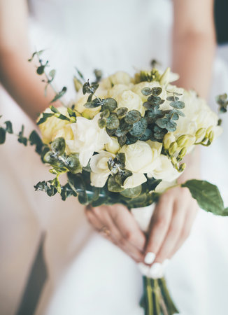 Close-up of a delicate beautiful wedding bouquet in the hands of the bride in a white dress.の写真素材