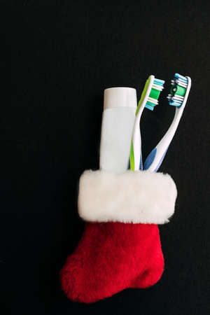 Red sock with two toothbrushes and a tube of toothpaste on a black background.の写真素材
