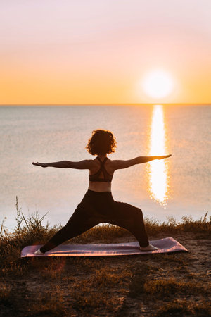 Vertical Yogi woman practices yoga at sunrise by the sea. Finding balance. Positive attitude, balance.の写真素材