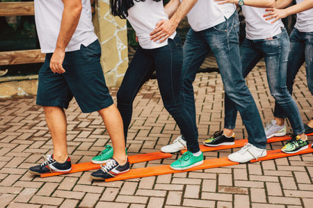 People stand with their feet on common wooden skis and move forward together. Teambuilding. High...