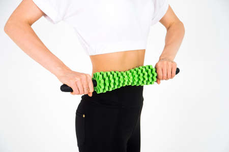 Close-up of a girl holding a massager in her hands and massaging the abdomen from cellulite and good appearanceの写真素材