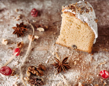 A piece of Easter dessert in a cut on a wooden table with flour and dried fruitsの写真素材