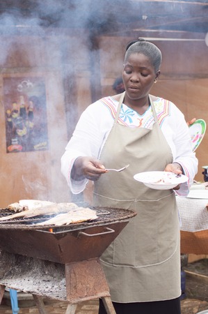This lady filled with smoke, is cooking on a grill her fish.のeditorial素材