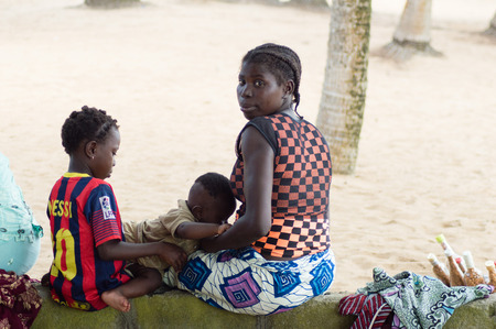 Abidjan, Cote d'Ivoire-august 29.2015: young woman with her two children rest in the shade of coconut treesのeditorial素材