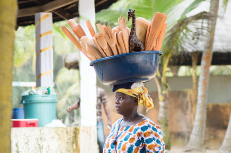 Abidjan, Ivory coast-august 29.215: a traveling shopping bowl on her head filled with art, walks to the beach for saleのeditorial素材
