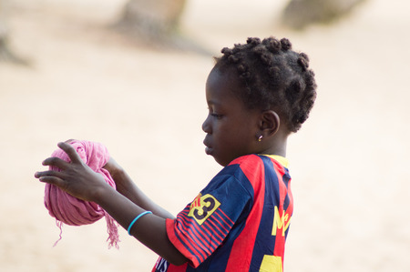 Abidjan, Ivory coast-August 29, 2015: A little girl Makes cushion with a piece of fabric That will serve her to carry her goods.のeditorial素材