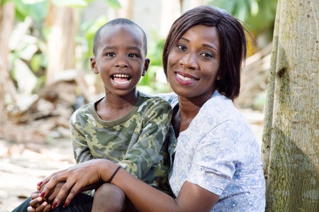 mother and son take the air in kind leaning against a tree.の写真素材