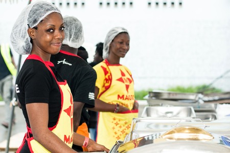 Abidjan, Ivory Coast, September 11, 2016: Young women waitresses to restore grilling feast of Abidjan. Standing behind different foods, thesis young women are dressed in yellow and black the first smiling looking at the cameraのeditorial素材
