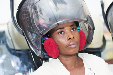 Placed young woman her head under a helmet hair to dry hair.の写真素材