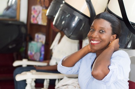smiling young woman sitting at the hair salon is in the process of arranging her hair.の写真素材