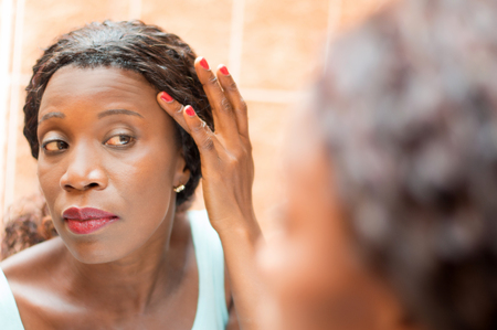 Young woman looks in the mirror in order to properly apply makeup.の写真素材