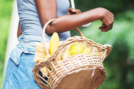 Young woman with an umbrella and a basket of fruit and bread.の写真素材