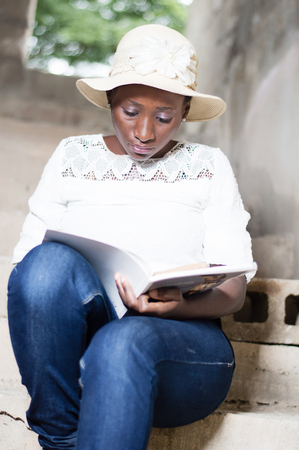 Beautiful young woman doing the reading on the stairs of an unfinished house.の写真素材