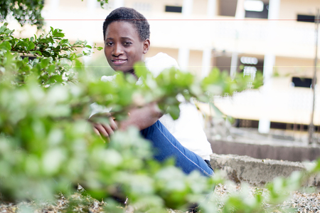 Young smiling woman sitting behind the foliage.の写真素材