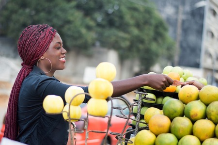 Smiling young woman takes her money in the hand of the fruit sellerの写真素材