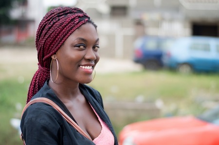 Portrait of a pretty smiling woman standing at the roadside watching the camera.の写真素材