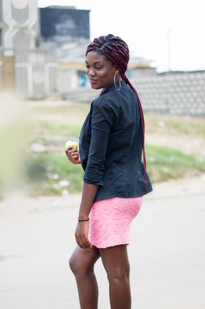Young woman holding an apple on the edge of the road.の写真素材