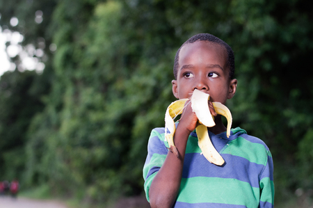 happy little boy eating a banana.の写真素材