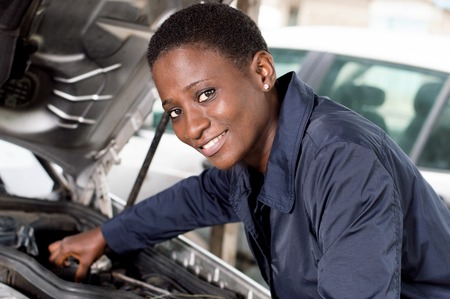 Young female mechanic repairs a car by putting the engine in good condition.の写真素材