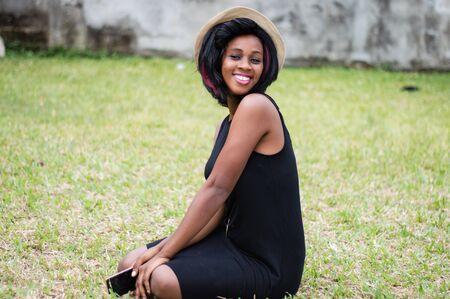 happy woman sitting alone in a park with mobile phone in handの写真素材