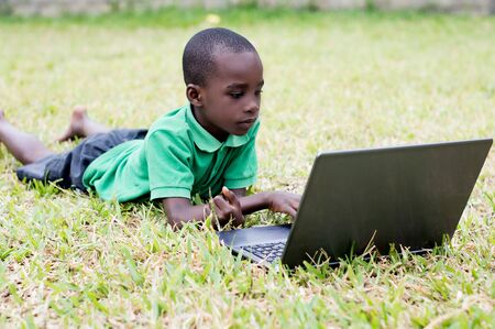 little boy lying in the nature with a laptopの写真素材