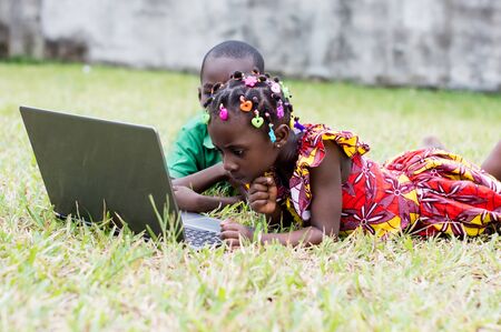 two children lying in the garden use a laptopの写真素材