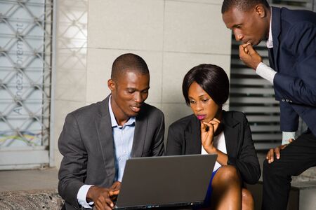 a business team sitting outside working together on laptopの写真素材