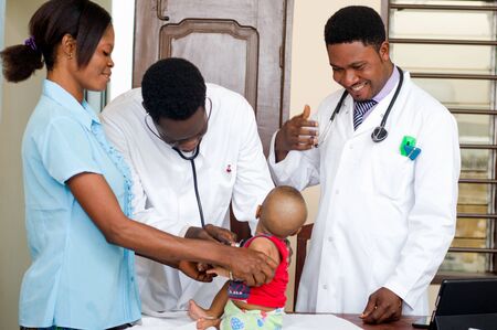 the doctors in white coats consult the baby together in a room of the hospital.の写真素材
