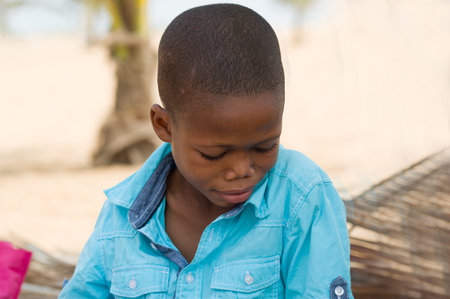 little boy sitting in the sand at the beach under the coconut trees.の写真素材