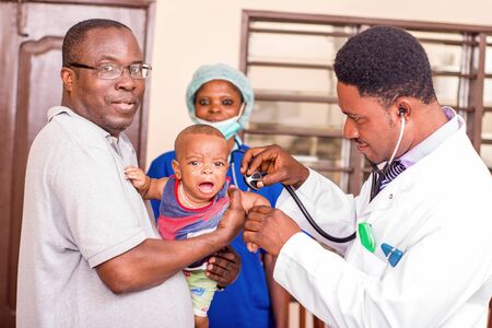 a young man catches his baby during the doctor examines him at the hospital.の写真素材