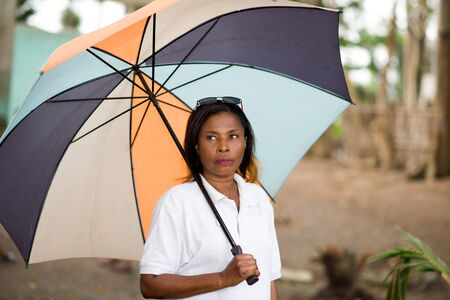 young woman strolling with a multicolored umbrella on her head.の写真素材