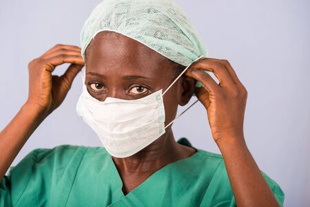 young female doctor standing up wearing a mouth cover while looking at the camera.の写真素材