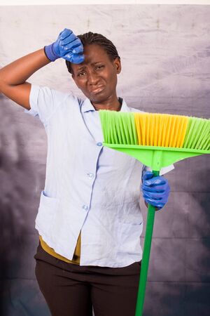 Household housework concept. Stressed and tired woman hand at forehead holding broom for cleaning.の写真素材