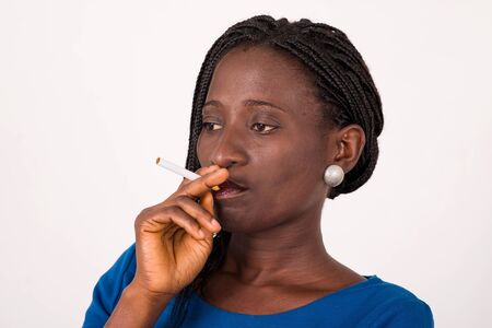 young girl standing on a white background and blue cigarette in her mouth, look at the camera..の写真素材