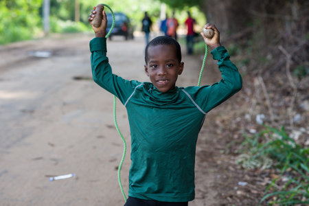 young boy in sportswear jumping rope and looking at camera smiling.の写真素材