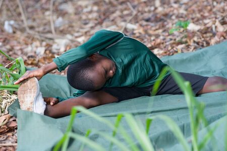 young boy sitting on a green carpet playing sportsの写真素材