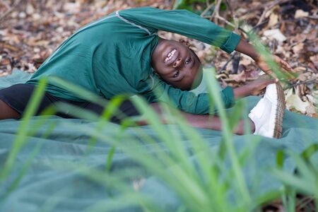 Little athletic boy warming up and stretching alone at the park. Lifestyle and sport conceptの写真素材